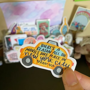 May include: Yellow taxi cab sticker with the text "There's a reason all the movies take place in New York City".