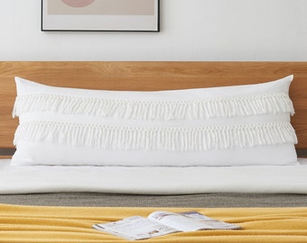 May include: White lumbar pillow with two rows of white fringe trim. The pillow is on a bed with a yellow blanket and a magazine.