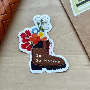 May include: A brown hiking boot with a bouquet of dried flowers on top. The boot has the text "Go CA Native" written on the side.