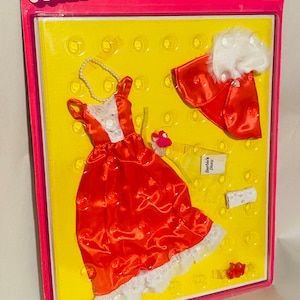 May include: A vintage Barbie Fashions set in its original packaging. The set includes a red polka-dot dress with white lace trim, a matching bolero with white faux fur, and accessories. The packaging features the Barbie logo and the text "for Card Christie & P.J. dolls too!"