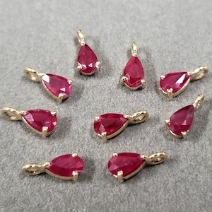 May include: Ten gold-tone teardrop-shaped pendants with red ruby-colored stones. The pendants are approximately 1 inch in length.