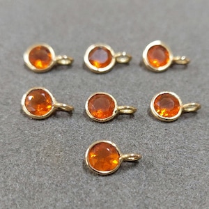 Puede incluir: Siete abalorios dorados con piedras redondas de cristal naranja. Cada abalorio tiene un pequeño bucle para sujetarlo a una pulsera o un collar.