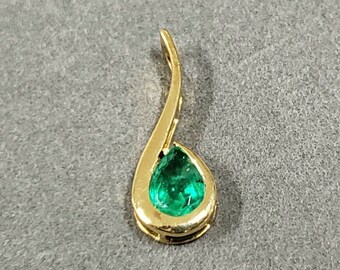 Könnte beinhalten: Ein goldener Anhänger mit einem birnenförmigen Smaragd.