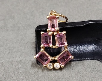 May include: A gold pendant with a cluster of pink and white gemstones in a geometric design.