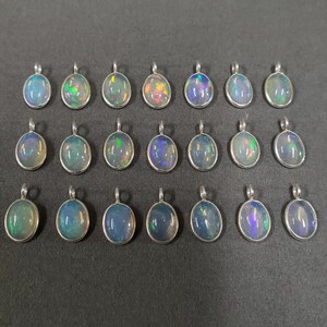 May include: Twenty oval-shaped opal pendants with silver settings. The opals are iridescent with shades of blue, green, and purple.