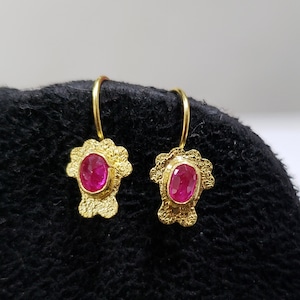 May include: A pair of gold earrings with pink oval-shaped gemstones set in a textured floral design.