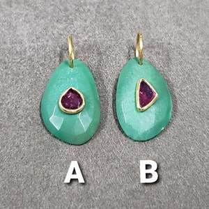 May include: Two green gemstone earrings with gold settings and a single pink gemstone in each. The earrings are labeled A and B.