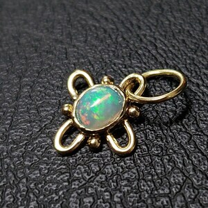 May include: A gold pendant with a delicate, intricate design featuring a round opal gemstone. The opal has a milky white base with flashes of green and blue.