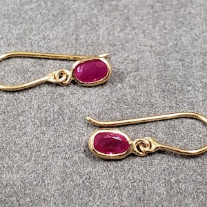 Peut inclure: Une paire de boucles d'oreilles en or avec de petites pierres précieuses rubis de forme ovale.