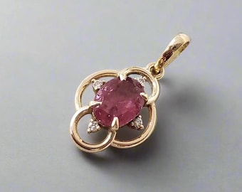 May include: A gold pendant featuring a large, oval-shaped, pink gemstone at the center. The gemstone is surrounded by a four-petal design with small, clear accent stones. The pendant has a loop for a chain.