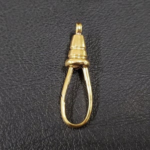 Puede incluir: Conector de cadena de metal dorado con un bucle en la parte inferior y una parte superior en forma de cono.