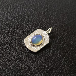May include: A silver pendant with a blue and green opal gemstone set in a textured silver frame.