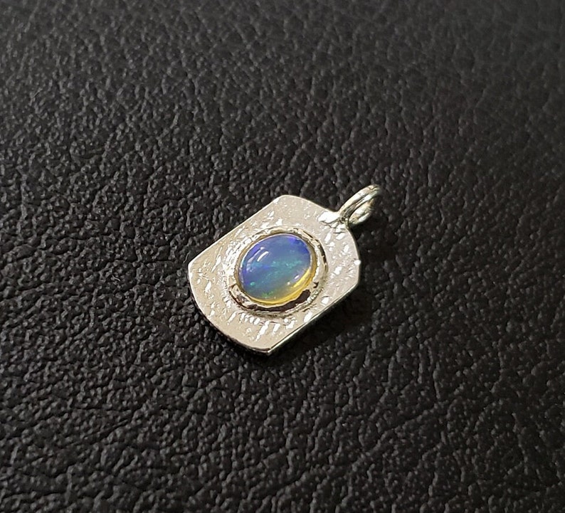 May include: A silver pendant with a blue and green opal gemstone set in a textured silver frame.