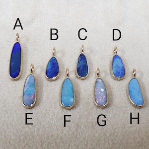 May include: Eight opal pendants in different colors and shapes, labeled A through H. The pendants are set in gold.