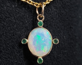 May include: A gold pendant necklace featuring a large oval opal gemstone surrounded by four smaller green gemstones.
