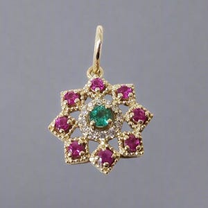 May include: A gold pendant featuring a green emerald gemstone surrounded by smaller diamonds and pink rubies.