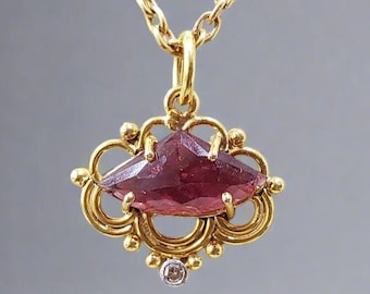 May include: A gold pendant necklace with a large, faceted, pink gemstone set in a delicate, ornate gold frame. A small, clear diamond is set below the gemstone.