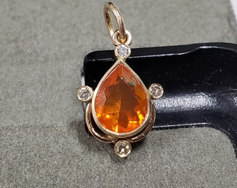 May include: A gold pendant featuring a teardrop-shaped orange opal surrounded by four small diamonds.