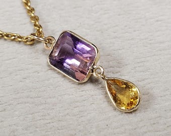 May include: A gold necklace with a rectangular purple gemstone and a teardrop-shaped yellow gemstone pendant. The chain and settings are gold. The gemstones are faceted and set in gold bezels.