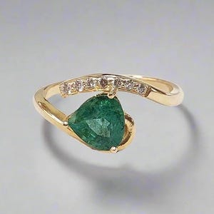 Close-up of 14k gold ring with pear-shaped Zambian emerald and diamond accents