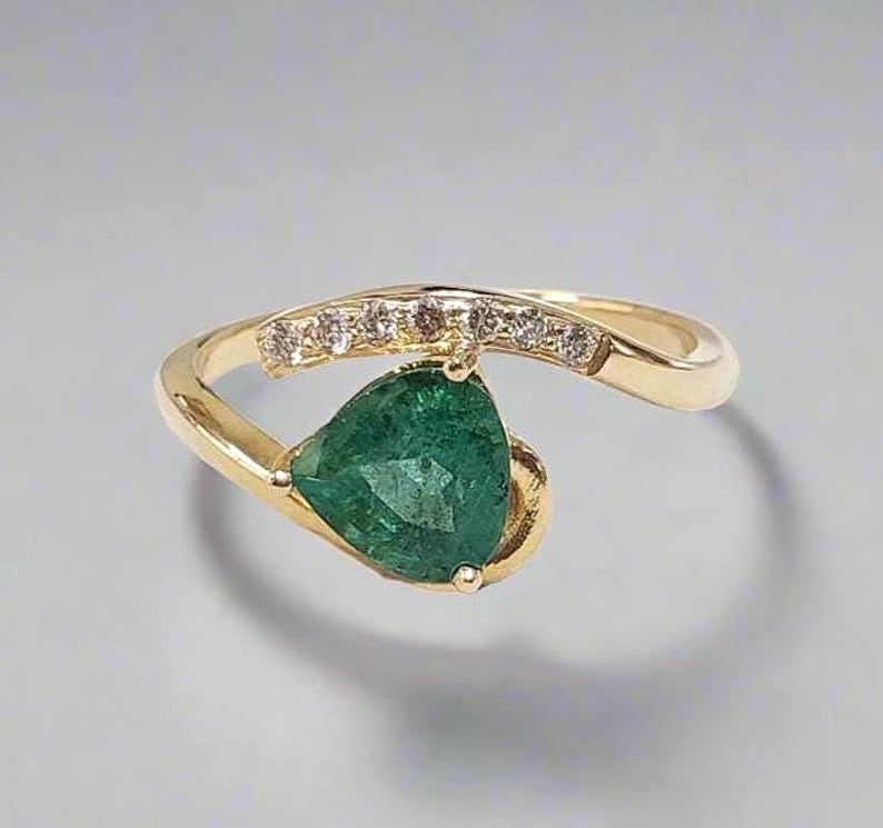 Close-up of 14k gold ring with pear-shaped Zambian emerald and diamond accents