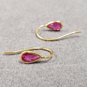 May include: A pair of gold earrings with pink teardrop-shaped gemstones.