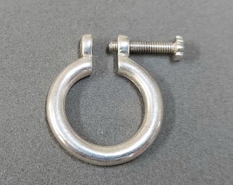 May include: Silver-toned metal clasp with a screw closure. The clasp is circular and has a smooth, polished finish.