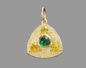 Könnte beinhalten: Goldener Anhänger mit strukturiertem dreieckigem Design. Er verfügt über einen zentralen grünen Edelstein und drei gelbe Edelsteine. Der Anhänger hat oben eine Schlaufe für eine Kette.