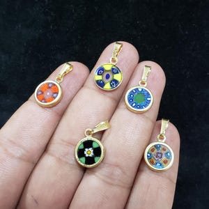 Puede incluir: Cinco colgantes dorados con diseños de mosaicos circulares coloridos. Los colgantes presentan varios patrones en rojo, naranja, azul, verde, amarillo y blanco. Cada colgante tiene un pequeño lazo para una cadena.