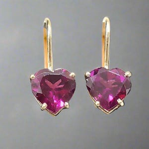May include: A pair of gold heart-shaped earrings with pink gemstones.