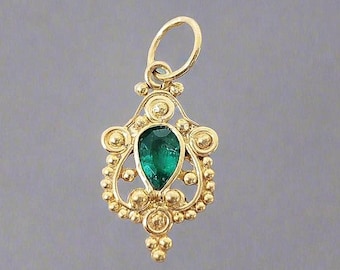 May include: A gold pendant with a pear-shaped, emerald-green gemstone at its center. The pendant features a detailed, ornate design with small gold beads and decorative swirls. The bail is a simple loop.
