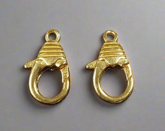 May include: Two gold-toned metal lobster claw clasps. The clasps are designed with a decorative, textured surface.