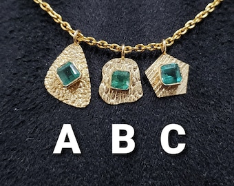 May include: A gold chain necklace with three pendants, each featuring a different textured design and a square green gemstone.