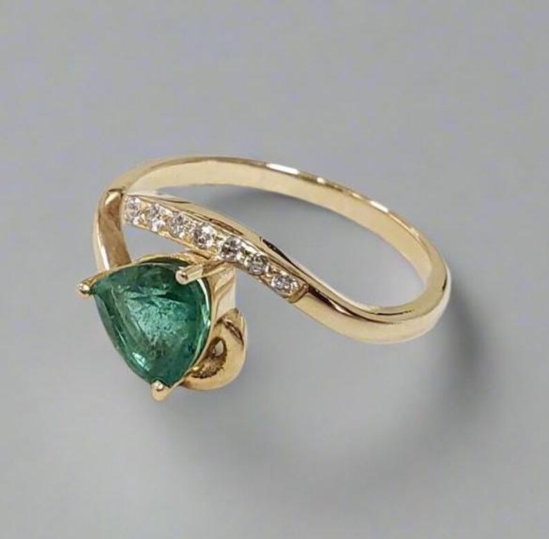 Elegant gold emerald diamond ring with pear cut gemstone on neutral background