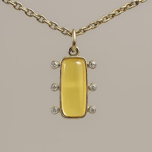 May include: A gold-toned necklace featuring a pendant with a rectangular, yellow-toned center stone. The pendant is accented with six small, round, clear gemstones. The chain is a linked design.