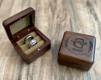 May include: Two wooden ring boxes. One box is open and contains two silver rings. The other box is closed and has the text "GAGNON 09.04.23" engraved on the top.