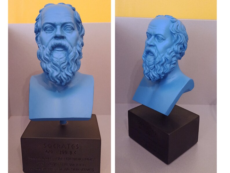 May include: A blue bust sculpture of Socrates on a black base. The base has the inscription "Socrates 470-399 B.C. " in Greek letters.