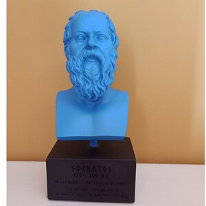 May include: A blue bust sculpture of Socrates, a Greek philosopher, on a black base. The base has the text "SOCRATES 470-399 B.C. "ALL I KNOW IS THAT I KNOW NOTHING" "I AM THE WORLD" - WHICH MOST WISE OBSERVES"