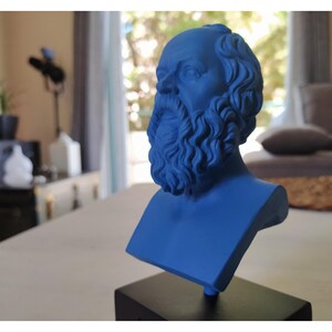 May include: A blue bust sculpture of a man with a beard and curly hair. The sculpture is on a black base.