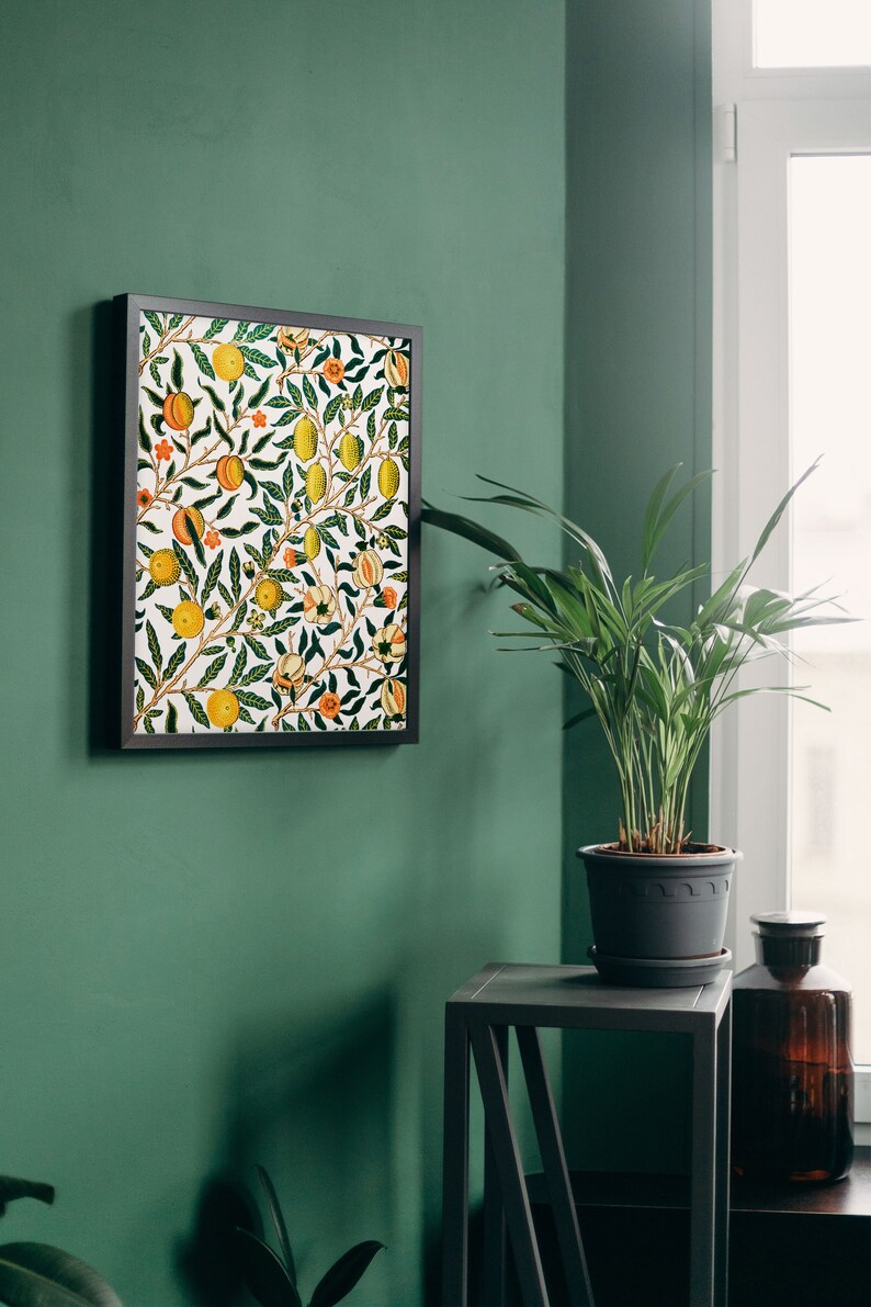 Puede incluir: Una impresi&oacute;n enmarcada de una ilustraci&oacute;n bot&aacute;nica vintage con un patr&oacute;n repetitivo de limones, naranjas y flores sobre un fondo blanco. La impresi&oacute;n est&aacute; colgada en una pared verde junto a una planta en maceta y una mesa peque&ntilde;a.