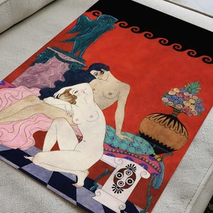 Close-up view of George Barbier’s 1920s Art Deco illustration showing rich details of the nude figures, intricate patterns, and signature. Set on a textured couch surface, the image highlights the quality of the giclée print and the ornate, vintage aesthetic of the artwork.