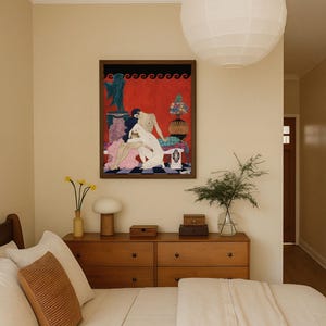 Art Deco print by George Barbier centered above a warm-toned dresser in a stylish, minimalist bedroom. The vintage scene of two nude women in an ornate setting adds a sensual, elegant accent, contrasting with the room’s neutral palette and soft textures.