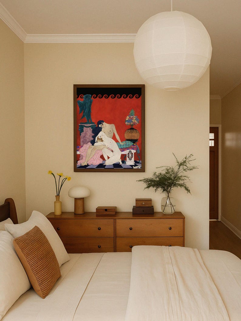 Art Deco print by George Barbier centered above a warm-toned dresser in a stylish, minimalist bedroom. The vintage scene of two nude women in an ornate setting adds a sensual, elegant accent, contrasting with the room’s neutral palette and soft textures.