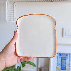 Toast Plate, handmade ceramic plate in toast shape. This plate looks like toast bread slice. Edges are slightly curved to upward. It is part of the bakery collection. Check our shop for more bakery collection items.