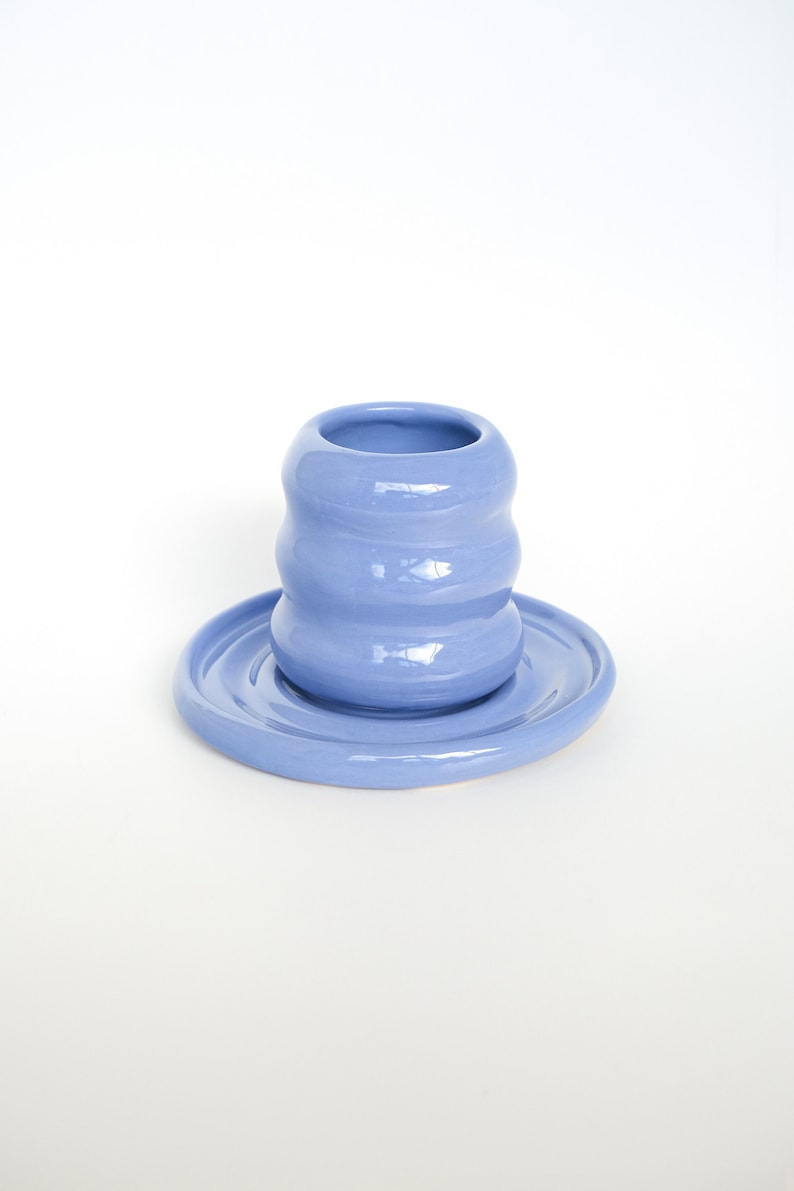 Puede incluir: Una taza de cer&aacute;mica azul claro con un dise&ntilde;o ondulado se asienta sobre un platillo a juego. La taza y el platillo est&aacute;n ambos esmaltados y tienen un acabado liso.