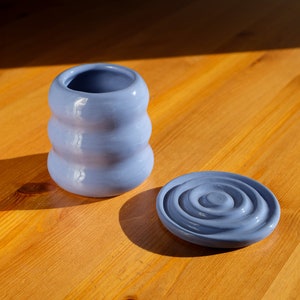 Puede incluir: Un recipiente de cer&aacute;mica azul con tapa. El recipiente tiene un dise&ntilde;o ondulado y texturizado, y la tapa tiene un dise&ntilde;o de c&iacute;rculos conc&eacute;ntricos.