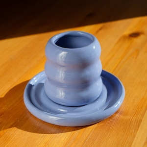 Puede incluir: Una taza de cer&aacute;mica azul claro con un dise&ntilde;o ondulado se asienta sobre un platillo a juego. La taza y el platillo est&aacute;n hechos de cer&aacute;mica esmaltada.