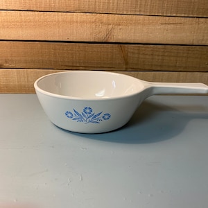 May include: White ceramic saucepan with a blue floral design. The saucepan has a single handle.