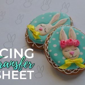 May include: Two decorated sugar cookies with bunny faces. The cookies are iced in blue and white with yellow bows. The text "ICING Transfer SHEET" is printed on the white background.