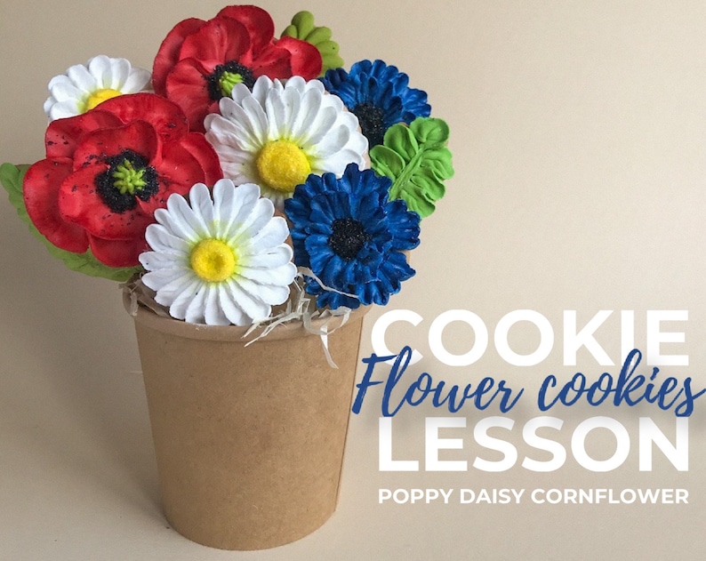 May include: A bouquet of decorated sugar cookies in a brown paper cup. The cookies are shaped like poppies, daisies, and cornflowers. The text "COOKIE Flower cookies LESSON POPPY DAISY CORNFLOWER" is below the cookies.